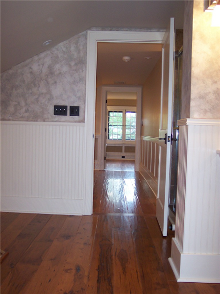 The painted beaded wainscot along with the distressed flooring in this 2nd floor remodel stays in tune with character of this older home.