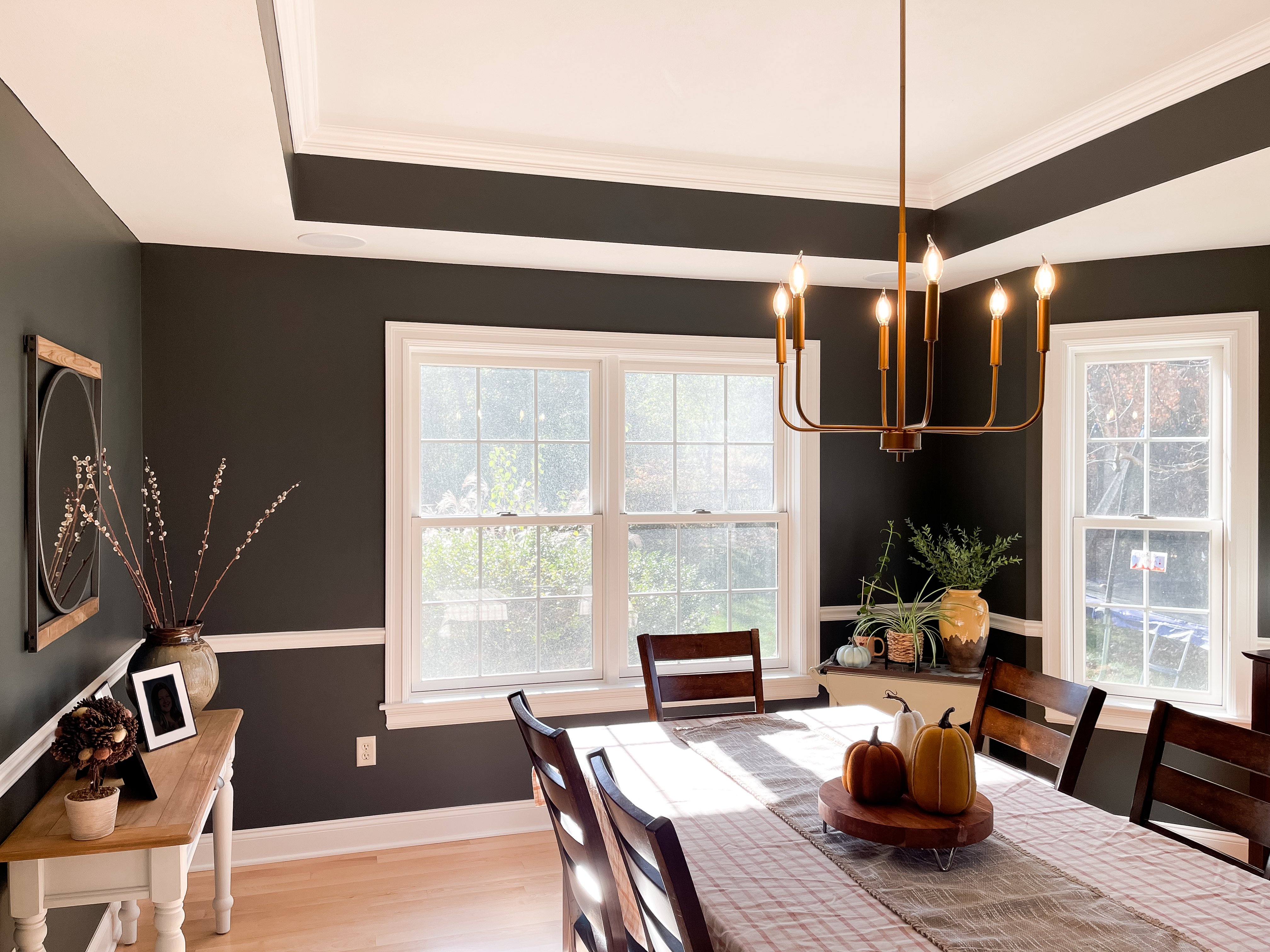 Dining room featuring a modern light fixture, large windows, and deep olive green walls.