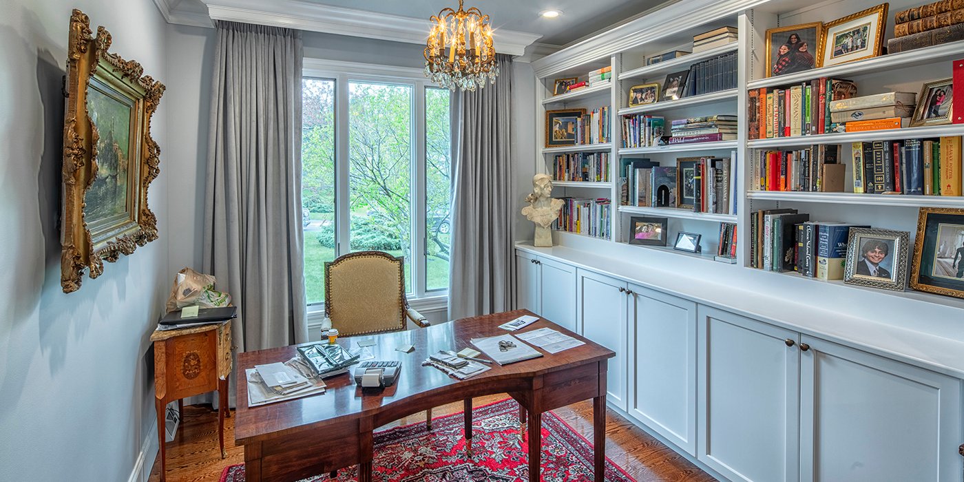 Home office with built-in bookcase, antique decor, and a large back window.