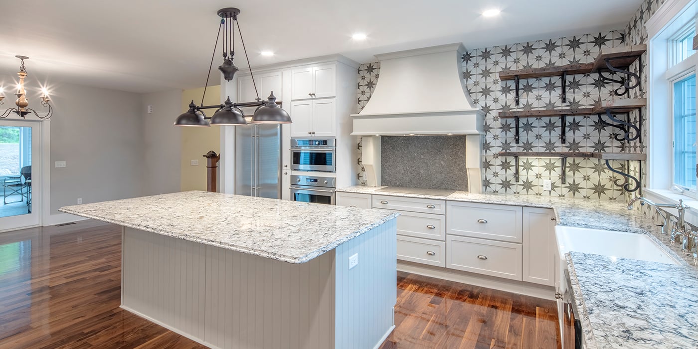 Kitchen with beautiful tile backsplash, quartz countertops and white cabinetry. 