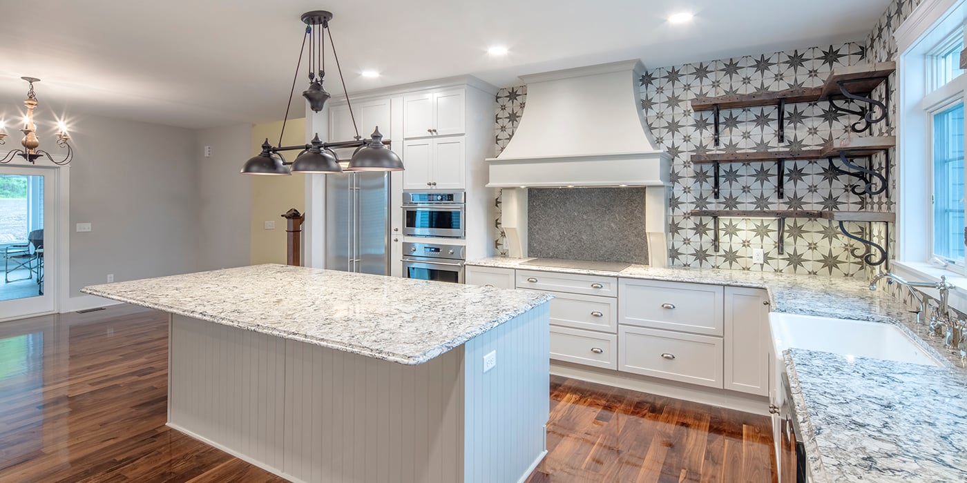 Kitchen with beautiful tile backsplash, quartz countertops and white cabinetry.