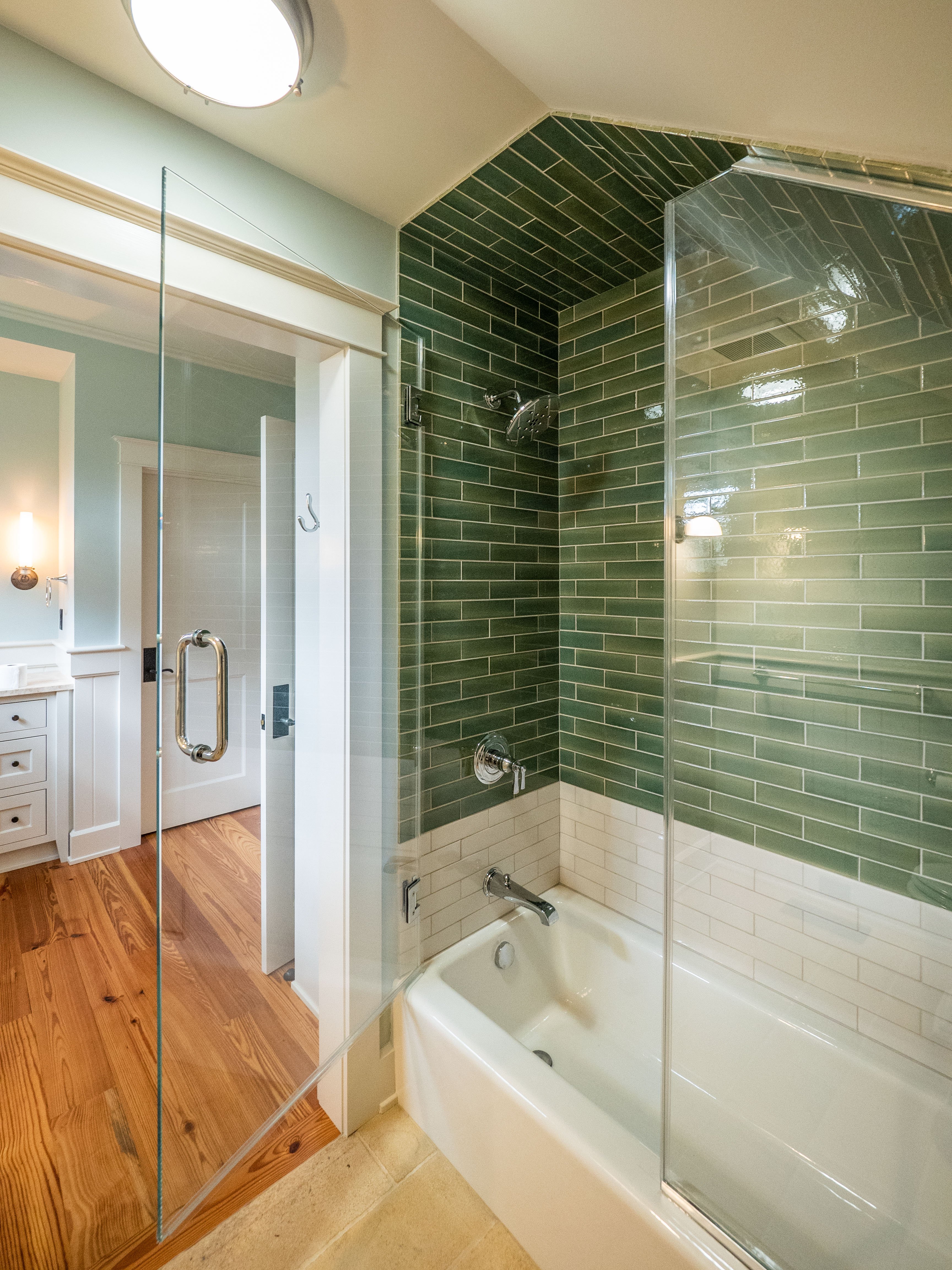 Bathroom with shower, tub, glass doors, and bold green subway tile.