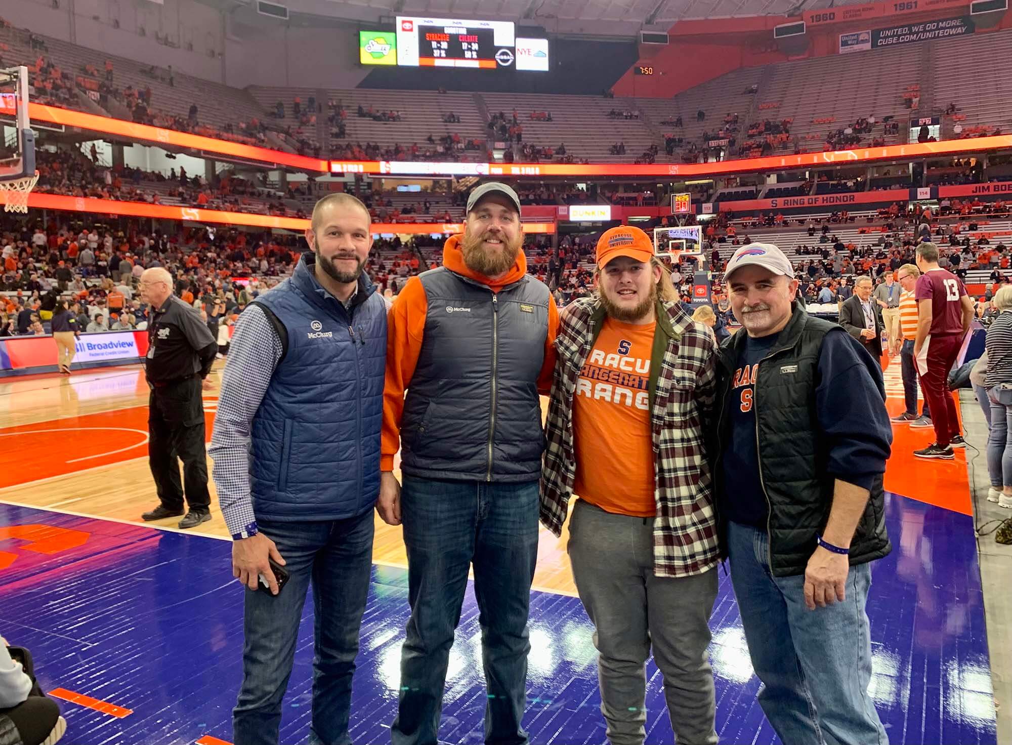 McClurg Remodeling crew members standing courtside at a Syracuse University basketball game, a thank-you gift from a Fayetteville homeowner after completing a historic window replacement project.