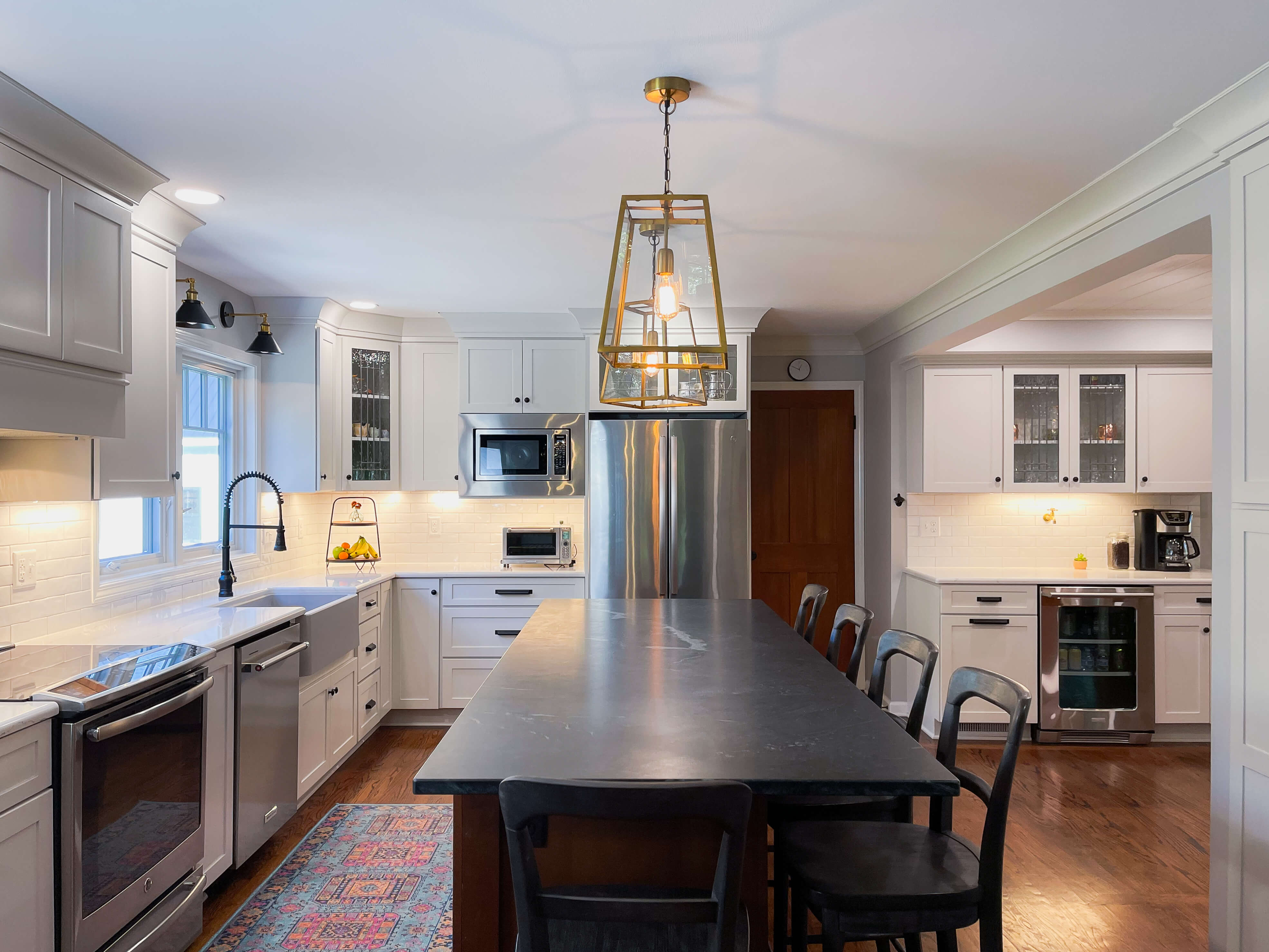 Kitchen with quartz island countertop, white cabinetry, stainless steel appliances, and warm pendant lighting in a clean, functional layout.