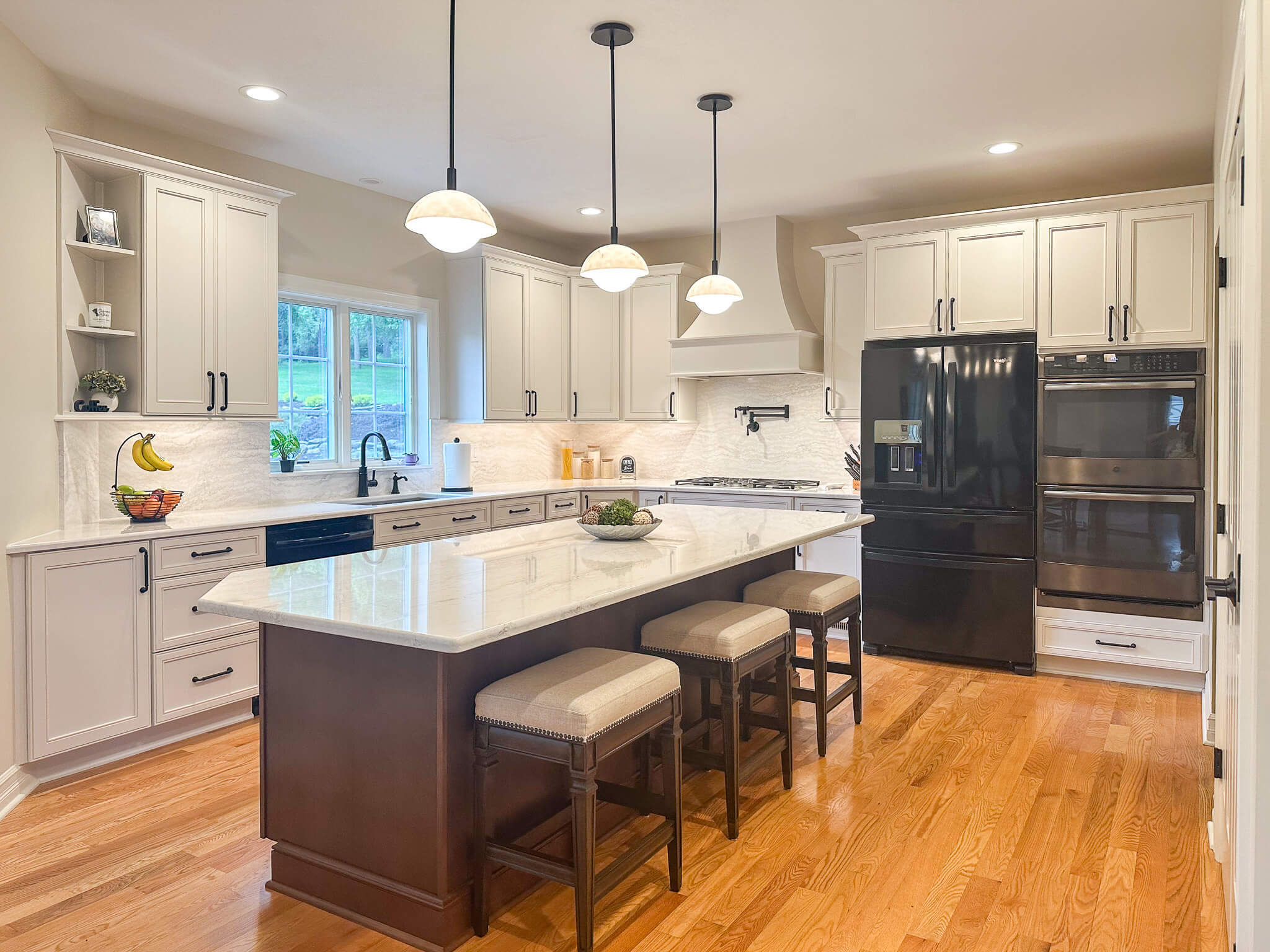 Kitchen featuring quartz countertops on the island and perimeter, white cabinets, integrated appliances, and balanced lighting.