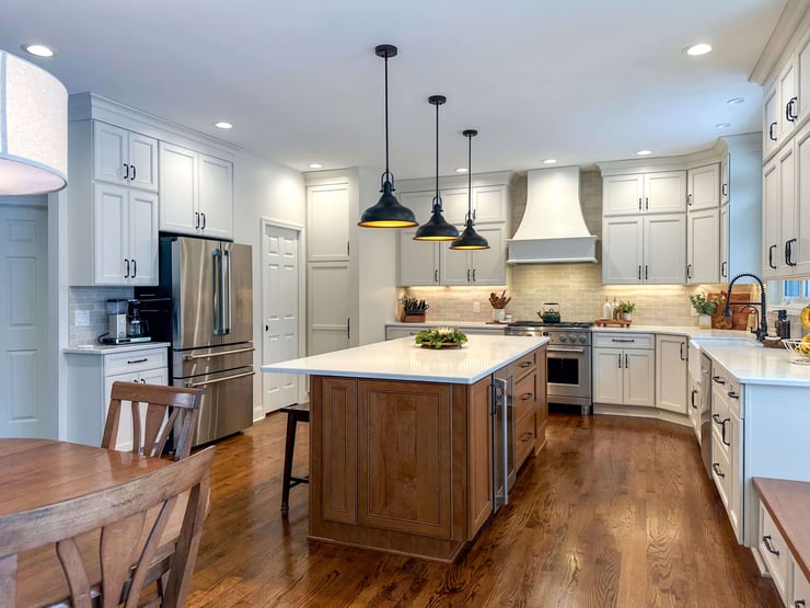 Spacious kitchen with hardwood floors, bright white countertops, and a mix of ambient, task, and accent lighting creating a functional and welcoming environment.