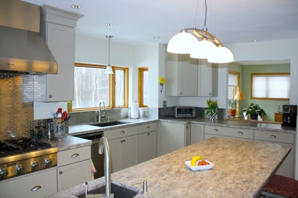 A three-lamp pendant fixture was place over the island. A matching pendant was selected to illuminate the main sink. Recessed lights were repositioned over work areas of the kitchen.