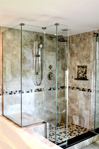 This custom mud set shower features ceramic tile floor and walls in a classic color palate. The glass surround provides an open feel to the space. A custom niche was created in the wall to hold soaps and shampoo. The seating area complements the soaking tub. The hand-held shower and wall mount rainfall showerhead and fixtures are brushed nickel.
