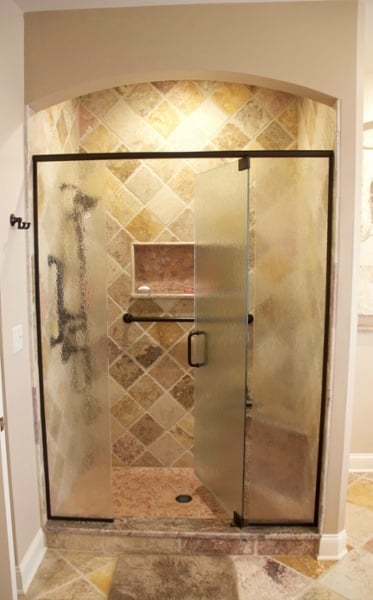 Framed embossed glass panels with a centered door provide easy access and privacy. Textured glass was used for this frameless pivot shower door. The glass is easy to clean, resists streaks and provides privacy.