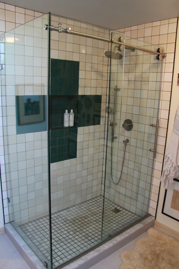 The clear glass enclosure and door reveal the custom tile design and accents in this shower. Designer hardware was used for the sliding glass door.