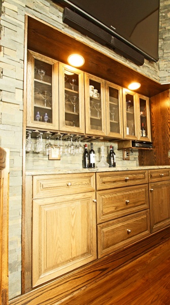 Built-in bar with oak cabinets by Bishop Cabinets and ledge stone wall and backsplash.