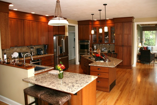 The cabinets in this kitchen are from Bishop Cabinets. Upper cupboards were installed at a lowered height for the homeowners and are trimmed with soffits that fill the space between the cabinets and ceiling. Other features include a beverage area with lit cupboards and glass doors. There is a pantry and large storage drawers on an island and along the perimeter of the kitchen.