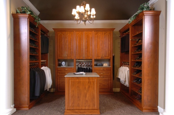 This custom walk-in closet features three walls of storage space and an island with a granite countertop.